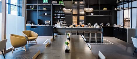 A modern kitchen with a long counter, built-in appliances, and a seating area with chairs and a table.
