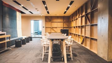 Une salle de conférence équipée d’une grande table, de six chaises et d’un mur en bois avec des étagères.