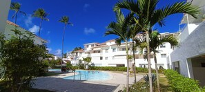 Un resort con piscina rodeada de palmeras y un edificio con balcones.