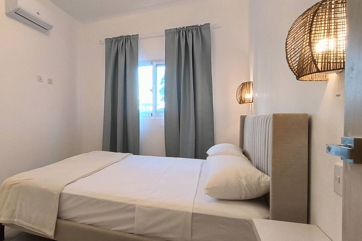 Une chambre à coucher avec un lit, une armoire, une étagère et une fenêtre avec des rideaux.