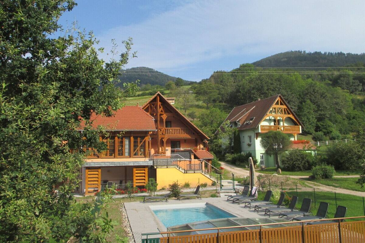 A wooden chalet with a swimming pool and lounge chairs.