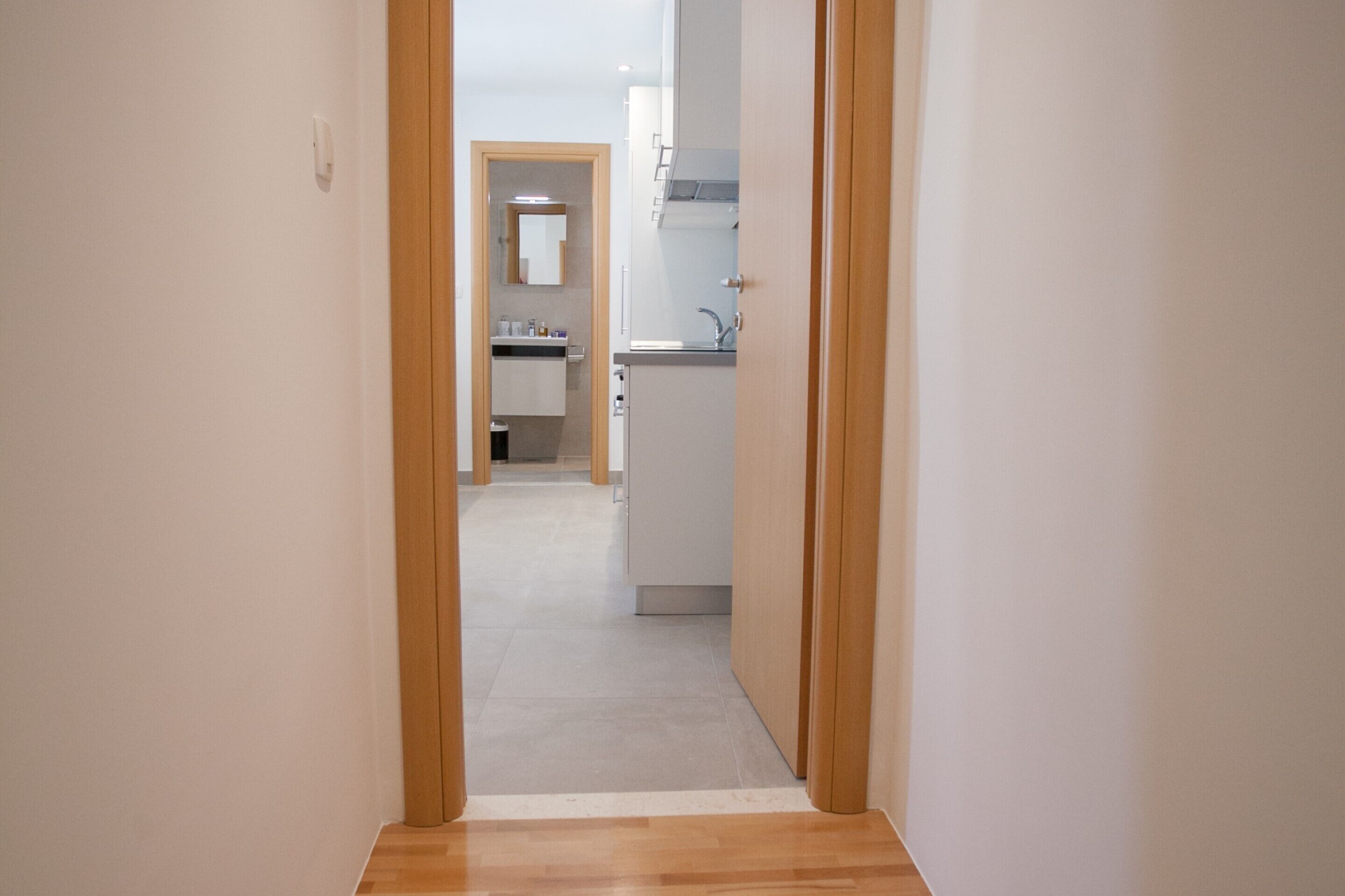 A narrow hallway leading to a kitchen area with a built-in oven and a sink.