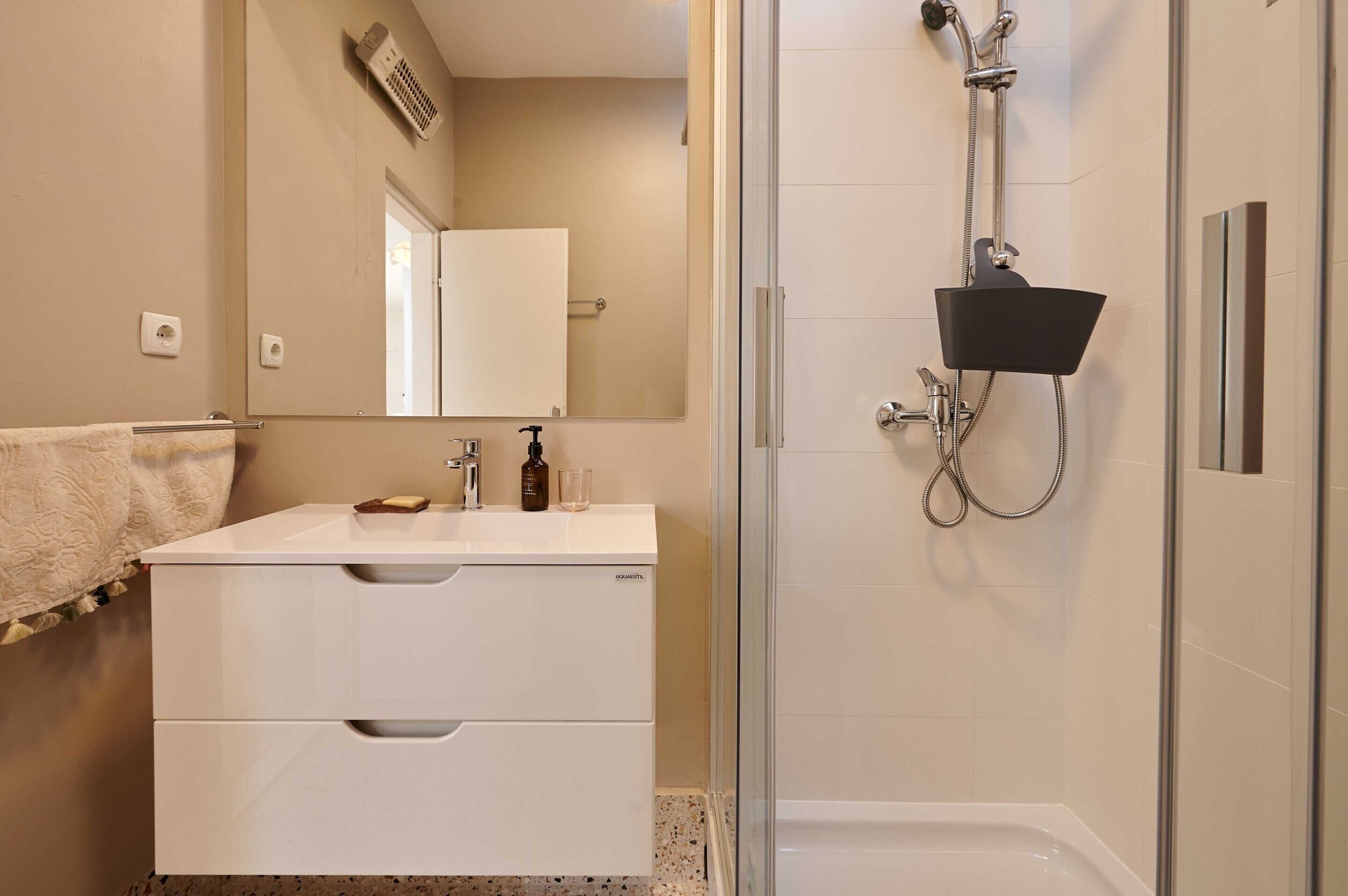 A modern bathroom with a white vanity, a glass shower enclosure, and a large mirror.