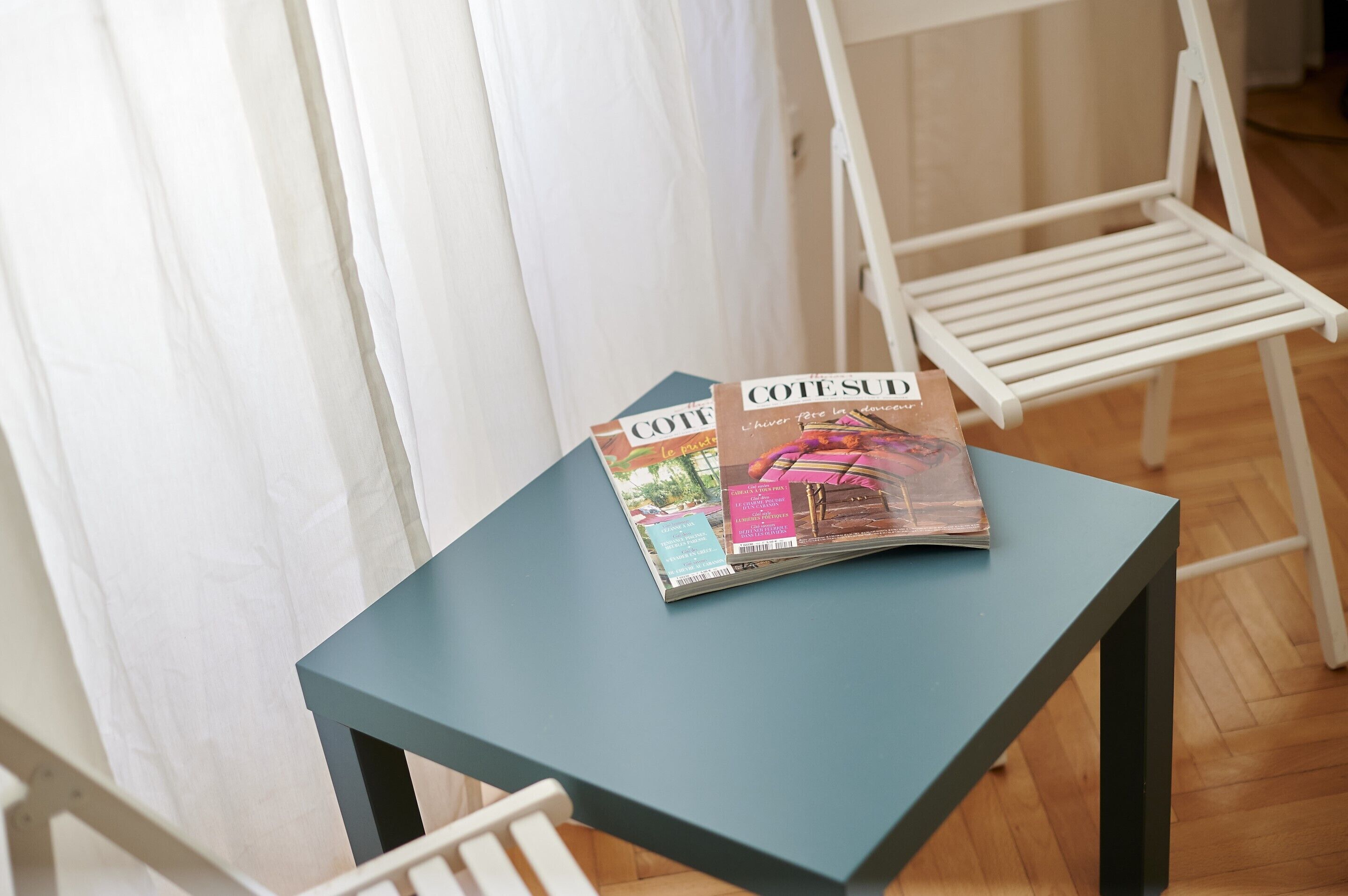 A magazine on a small table with a chair nearby.