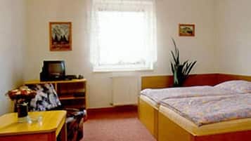 Un dormitorio con cama, escritorio, silla, radiador y ventana con cortinas.