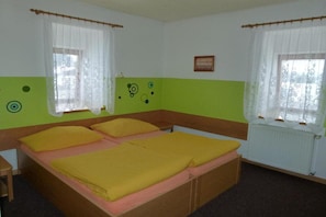 A room with a bed, two windows with curtains, a radiator, and a small picture on the wall. - Pelikan Hotel (Marianske Lazne)