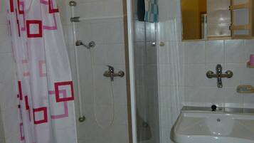 Un baño con ducha, lavabo y espejo.