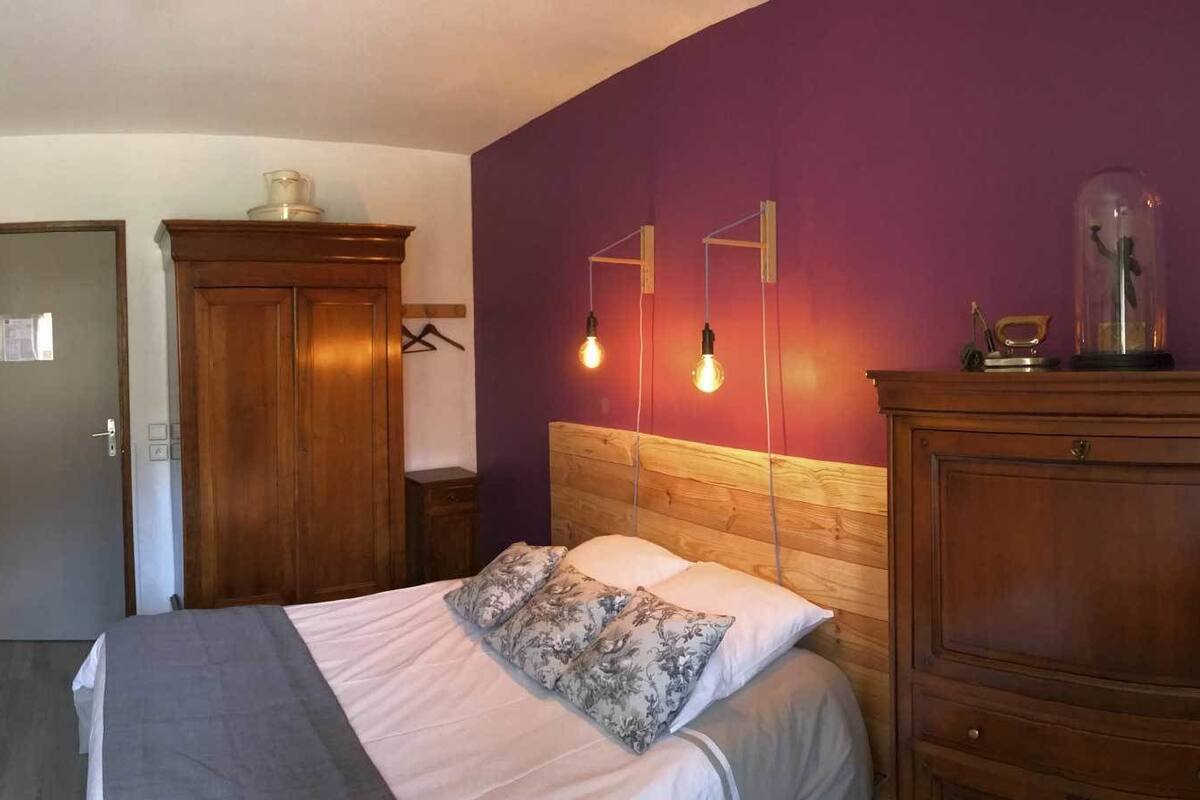 Ein Hotelzimmer mit Bett, Holz-Kopfteil, Spiegel, Kleiderschrank und Tür.