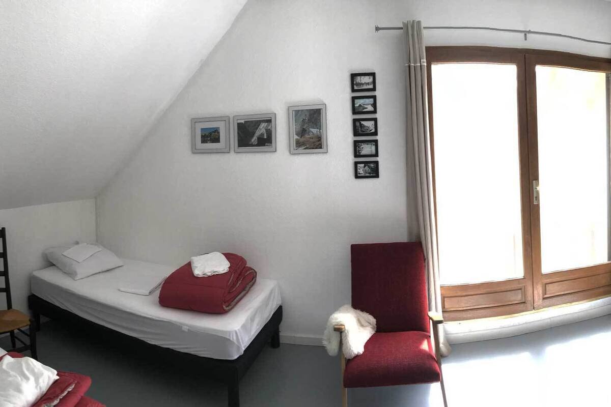 Ein Schlafraum im Schlafsaalstil mit Etagenbetten, einem Einzelbett, einem Stuhl und einem Heizkörper.