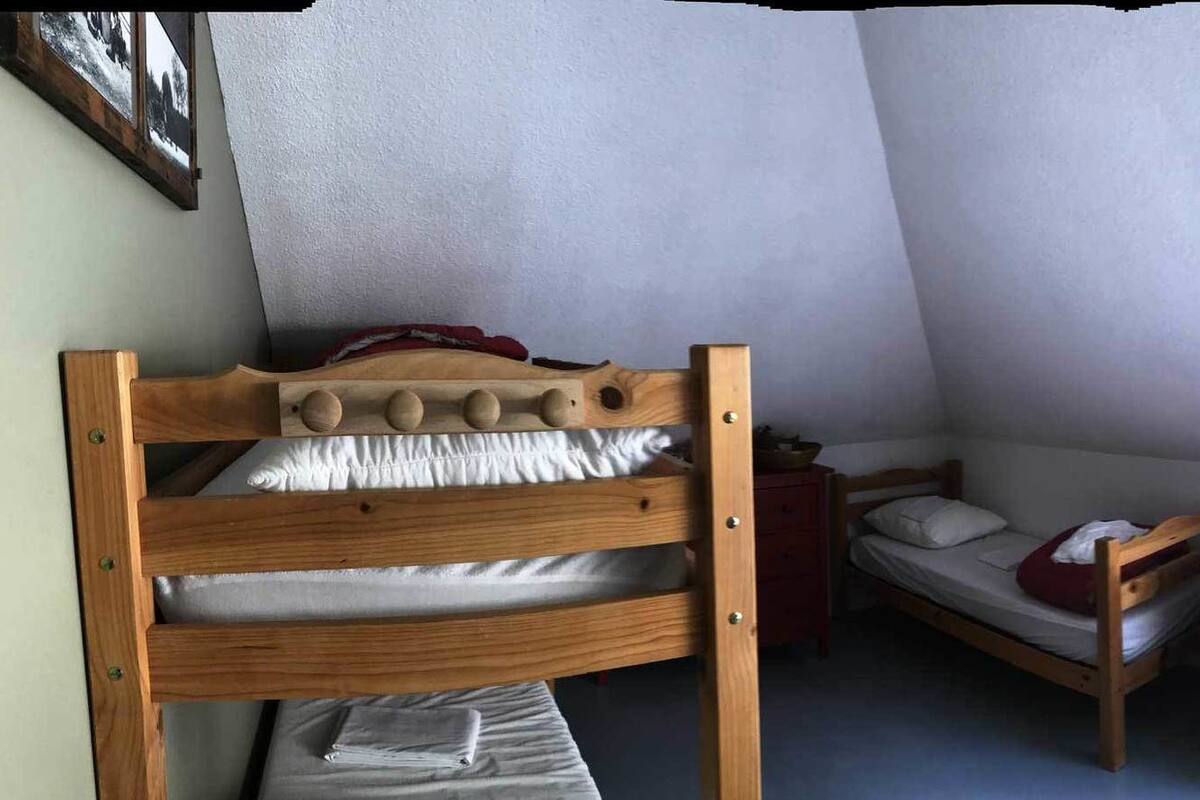 Ein Schlafsaalzimmer mit Etagenbetten, einem kleinen Schreibtisch und einem Fenster.