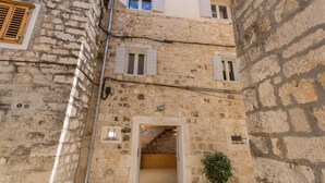 A narrow stone building with a small entrance and a staircase leading to an upper floor. - Casa Sepia (Trogir)