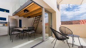 A modern kitchen with a dining area, a staircase, and a balcony with outdoor seating. - Casa Sepia (Trogir)