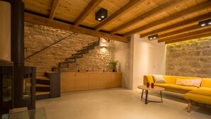 A modern interior with a stone wall, wooden staircase, a yellow sofa, and a glass table. - Casa Sepia (Trogir)