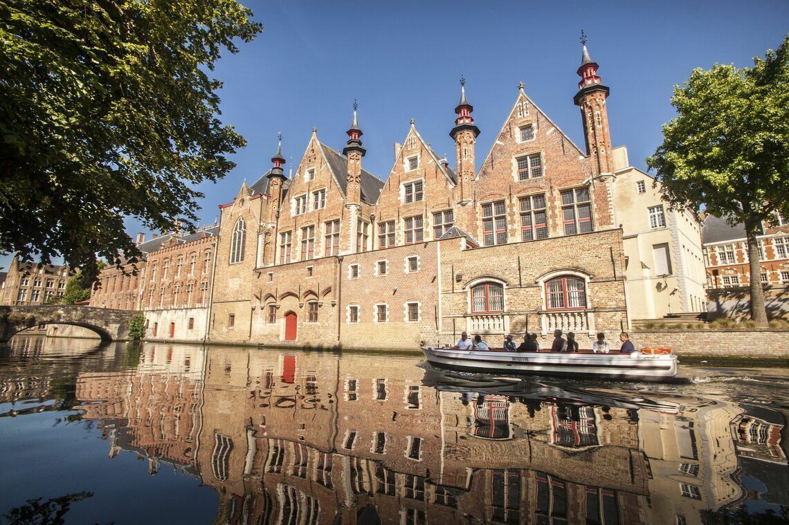Ein historisches Gebäude mit mehreren Türmen und einer roten Tür, das sich in einem ruhigen Fluss spiegelt.