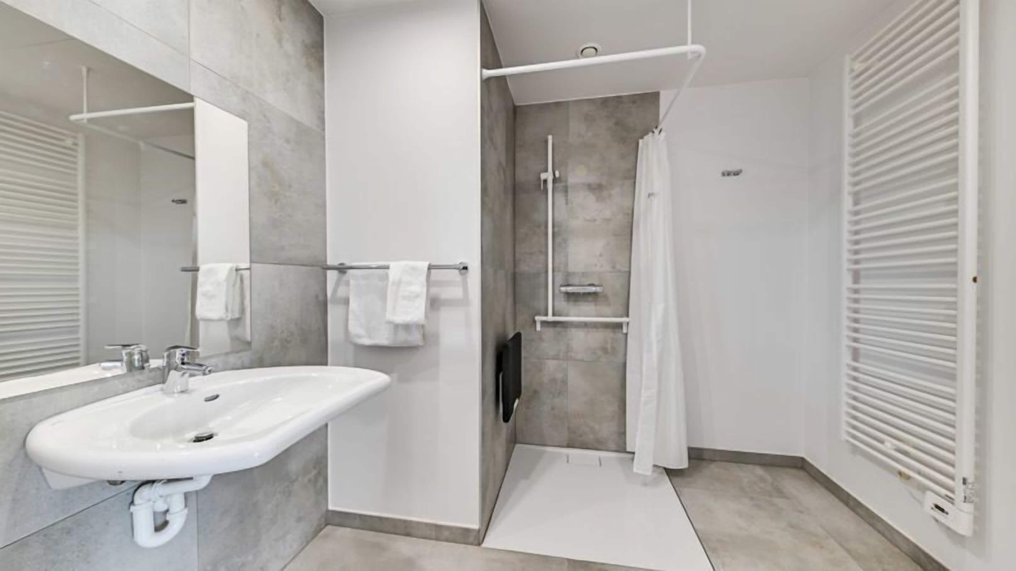 Une salle de bain moderne dotée d’un grand lavabo, d’une cabine de douche en verre et d’une douche à l’italienne.