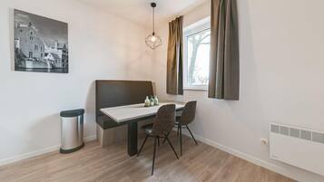 Una zona menjador moderna amb taula, cadires, llum penjant i finestra amb cortines.