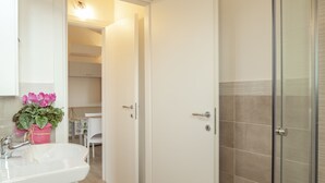 Un baño con lavamanos, ducha y puerta que da a un dormitorio.
