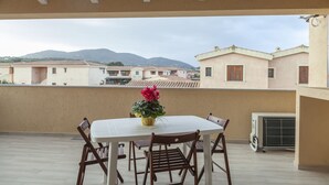 Una terraza con una mesa, sillas, una planta en maceta y un equipo de aire acondicionado.