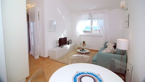A modern living room with a TV, sofa, and coffee table. - Apartment Flynn (Okrug)