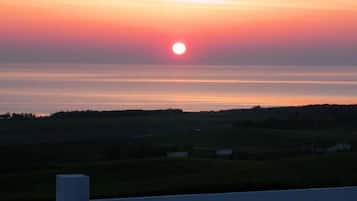 Un coucher de soleil sur un paysage rural, avec des champs et un horizon lointain.