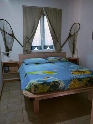 Un dormitorio con cama, cortinas, un ventanal y dos ventiladores de pared.