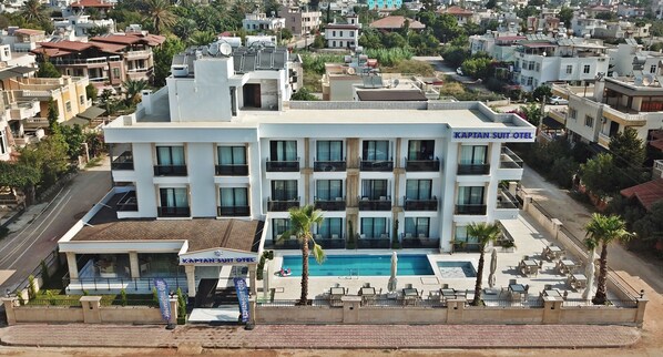 Un hotel de varios pisos con piscina, balcones y un cartel que dice "Kaptan Suit Hotel".