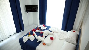 A hotel room with a bed, a flat-screen TV mounted on the wall, and a window with curtains. - Kaptan Suit Otel (Silifke)