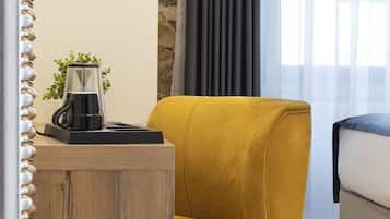 Ein modernes Zimmer mit einem Holztischchen, einem gelben Sessel, einem Bett und einer Kaffeemaschine.