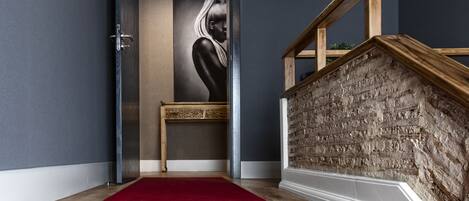 Un pasillo moderno con alfombra roja, una escalera de madera y una obra de arte colgada en la pared.