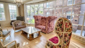 A spacious living room with a large window, a chandelier, and a fireplace. - The Stella Hotel & Ballroom (Kenosha)