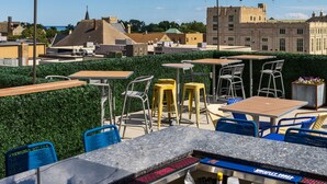 An outdoor seating area with tables and chairs, overlooking a cityscape with historic buildings. - The Stella Hotel & Ballroom (Kenosha)