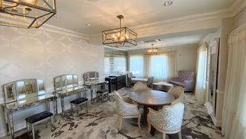 A spacious dining area with a round table and chairs, a bar area with mirrored cabinets, and a large window with curtains.