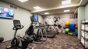 Un gimnasio con cintas de correr, bicicletas estáticas y pelotas de ejercicio.