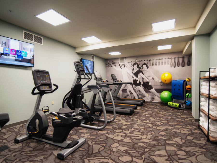 Un gimnasio con cintas de correr, bicicletas estáticas y pelotas de ejercicio.