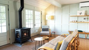 Een gezellige woonkamer met een houtkachel, rieten meubels en een boekenkast.