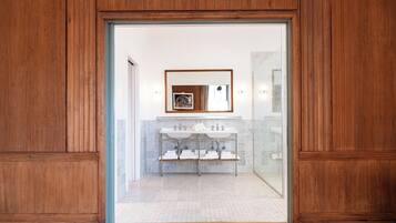 A wooden-framed doorway leading to a bathroom with a white sink and a framed picture above it.