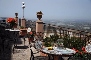 A terrace with a table set for two, featuring a view of the landscape. - Albergo villa nobile (Chiaramonte Gulfi)