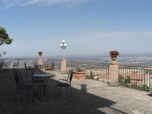 An outdoor terrace with a table and chairs, a lamp, and flower pots. - Albergo villa nobile (Chiaramonte Gulfi)
