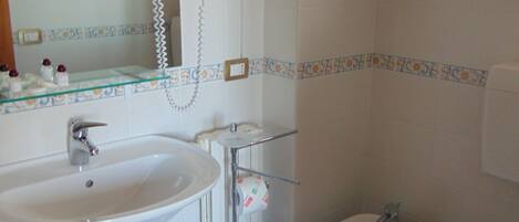 A bathroom with a sink, bidet, toilet, and a mirror.