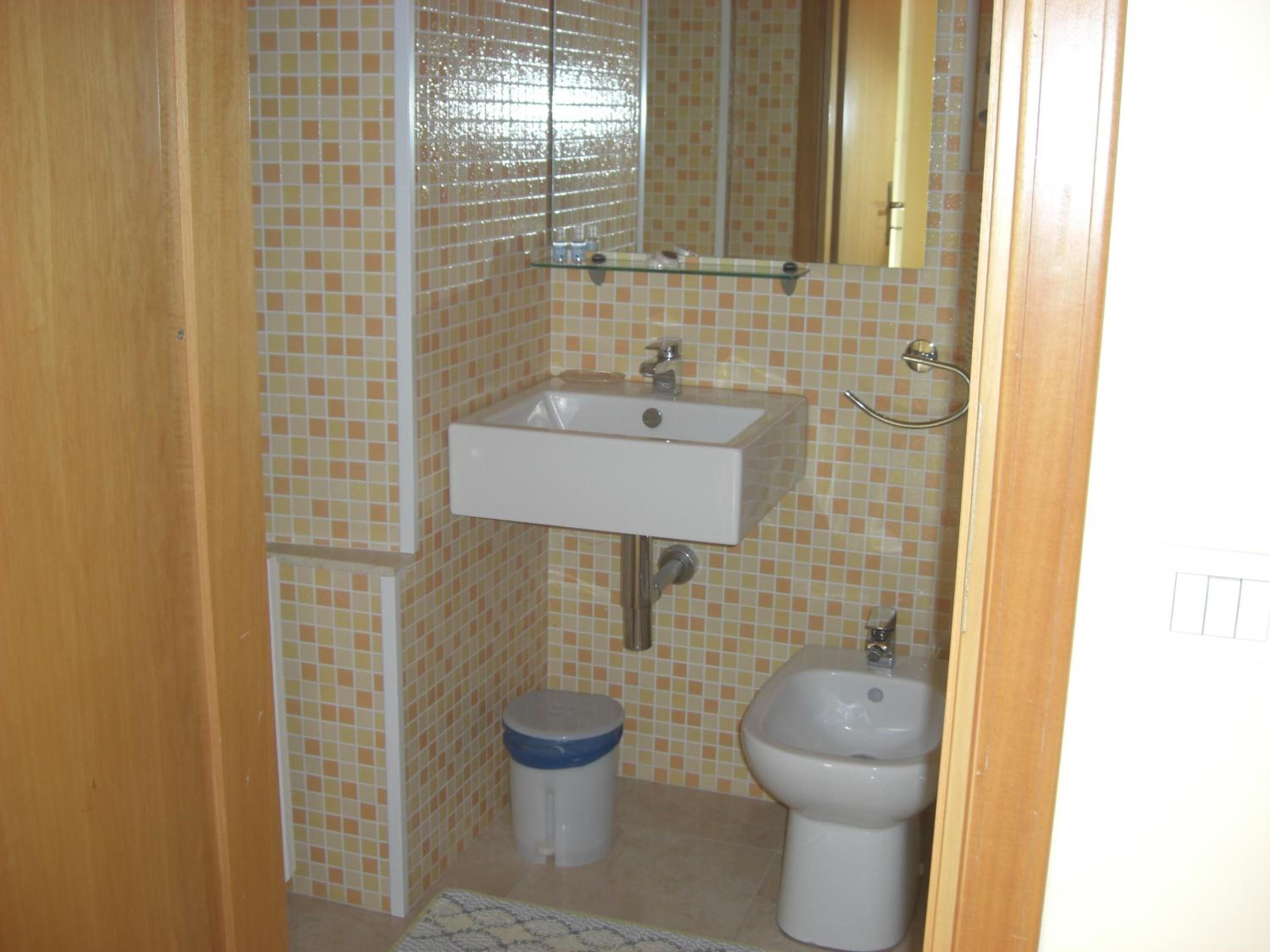 A small bathroom with a sink, bidet, and toilet.