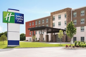 Un bâtiment de la chaîne Holiday Inn Express & Suites, doté d’un design moderne, avec une entrée abritée et un parterre aménagé à l’avant.