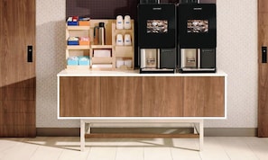 Cozinha moderna com duas máquinas de café, um armário de madeira e bancada com caixas organizadoras.