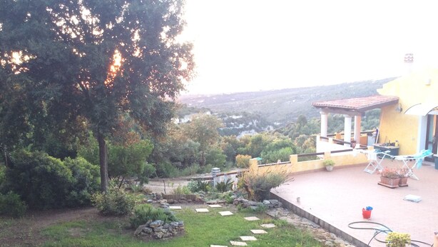 A garden with a patio area, stone steps, and a view of the surrounding landscape. - La Valle Dei Corbezzoli (Sassari)
