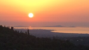 A sunset over a body of water with a distant shoreline. - La Valle Dei Corbezzoli (Sassari)