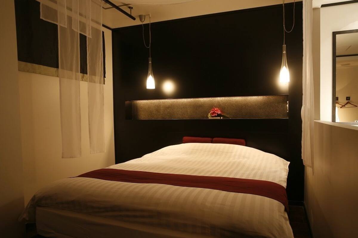 Une chambre d’hôtel comprenant un lit, une table de chevet, un miroir et un luminaire suspendu.