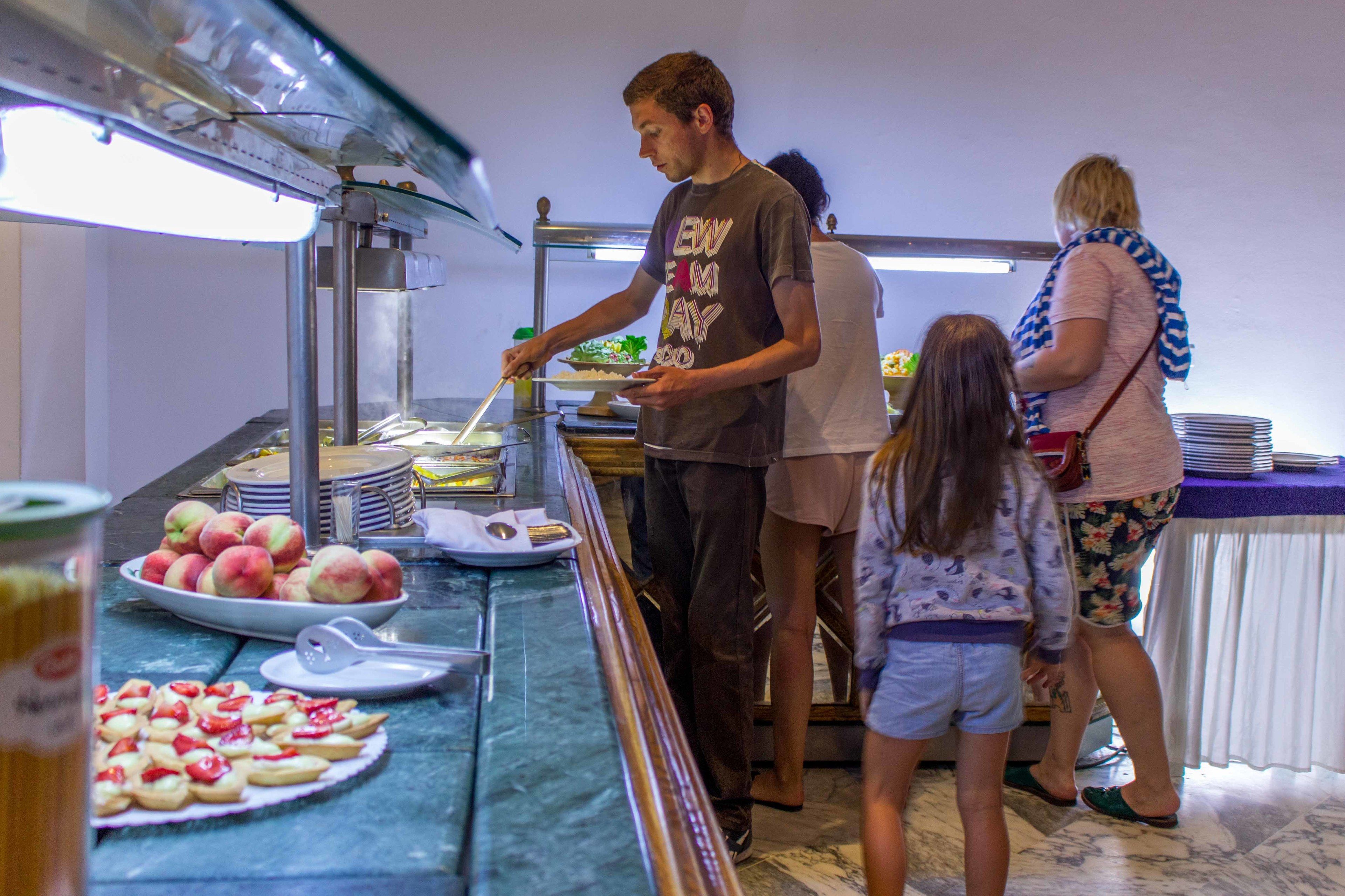 A buffet setup with a variety of food items on display, including fruits and pastries.