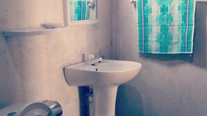 Un baño con inodoro, lavamanos y una toalla colgada en la pared.