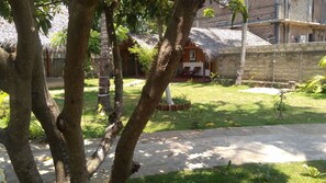 A courtyard with a thatched-roof building, a paved walkway, and surrounding greenery. - Surf Gangs Hotel Arugambay (Arugam Bay)