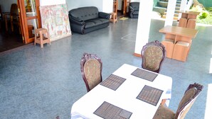 Amplia sala de estar con sofá, mesa de comedor y sillas. Una escalera conduce a un nivel superior.