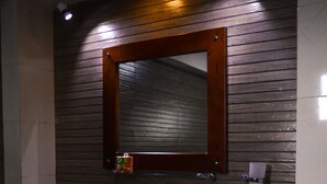 Un baño con un lavabo blanco, paneles de madera en la pared, un espejo y artículos de aseo en la encimera.
